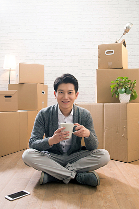 青年男人坐在地板上喝水照片