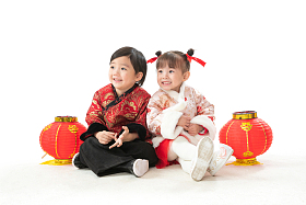 兄妹两人穿新衣服坐在地上庆祝新年