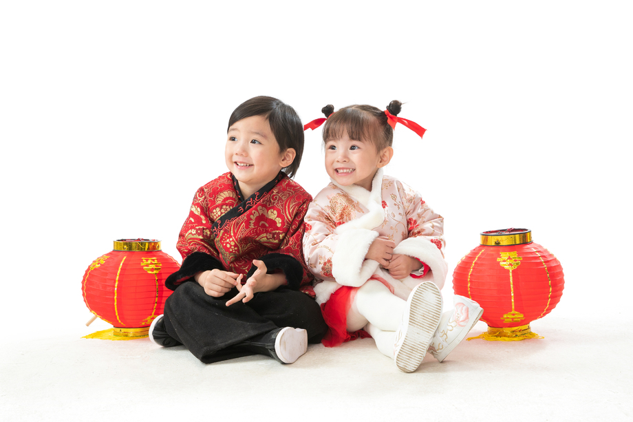 兄妹两人穿新衣服坐在地上庆祝新年