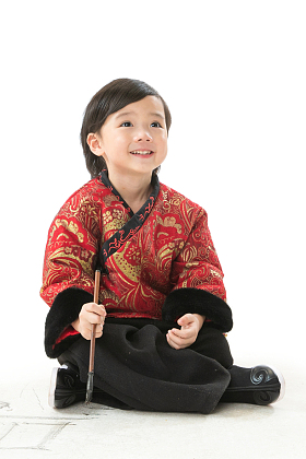 小男孩盘腿坐着拿毛笔写字图片