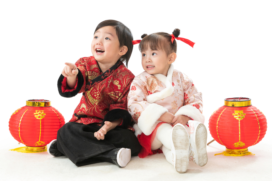 兄妹两人穿新衣服坐在地上庆祝新年