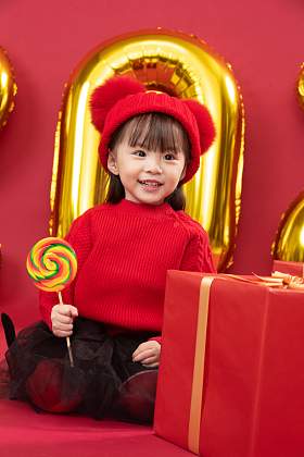 小女孩过年穿新衣服手拿棒棒糖