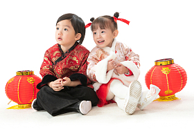 兄妹两人穿新衣服坐在地上庆祝新年