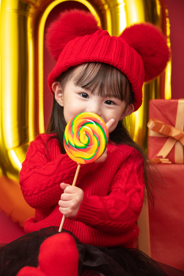 小女孩过年穿新衣服手拿棒棒糖 小女孩过年穿新衣服手拿棒棒糖