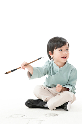 小男孩盘腿坐着拿毛笔写字图片