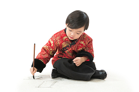 小男孩盘腿坐着拿毛笔写字图片