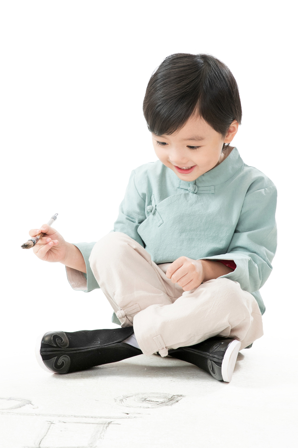 小男孩盘腿坐着拿毛笔写字图片