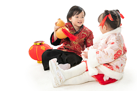 兄妹两人穿新衣服坐在地上庆祝新年