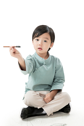 可爱的小男孩坐在地上用毛笔写字