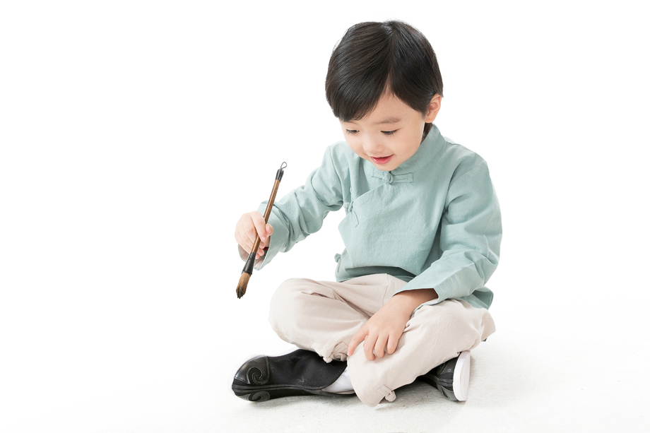 可爱的小男孩坐在地上用毛笔写字 可爱的小男孩坐在地上用毛笔写字