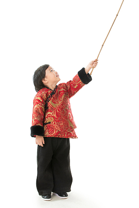 过新年的小男孩拿着竹竿玩耍图片