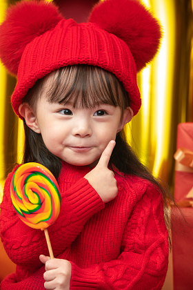 过新年的小女孩拿着棒棒糖照片