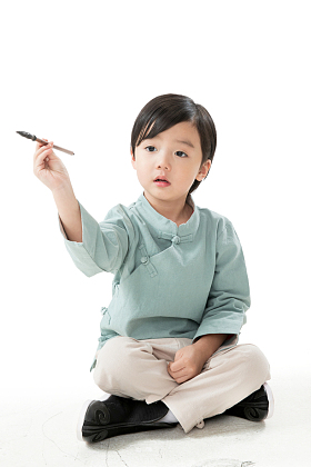 可爱的小男孩坐在地上用毛笔写字