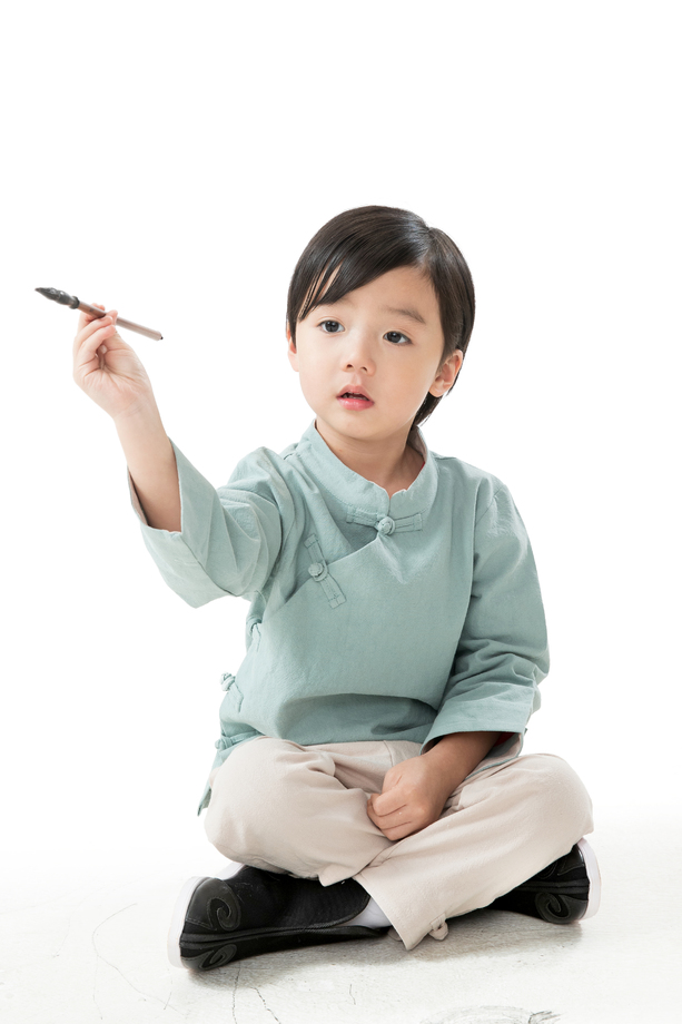 可爱的小男孩坐在地上用毛笔写字