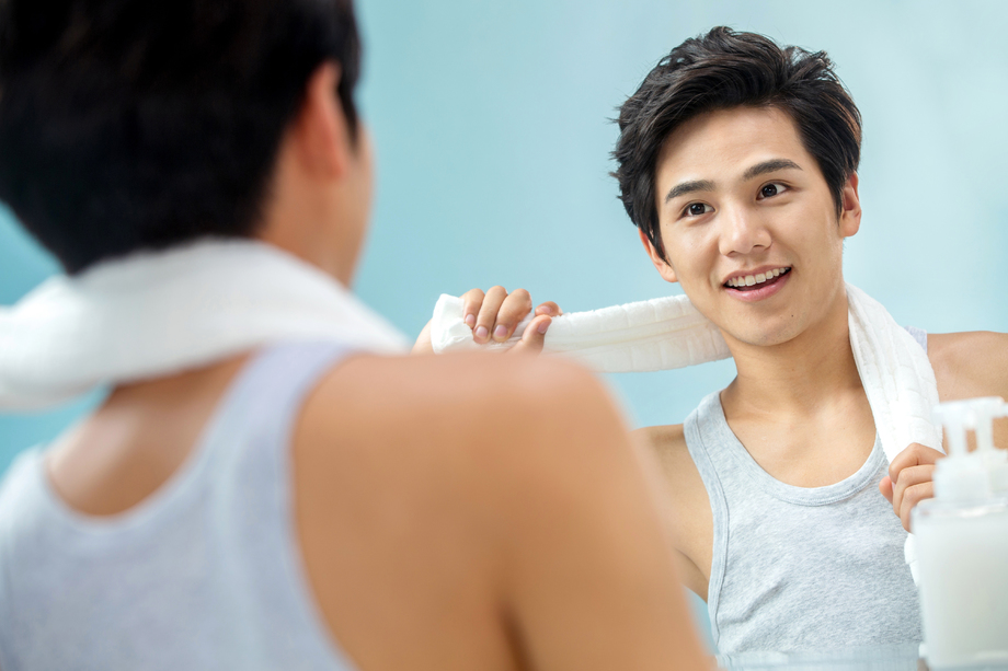 自信的年轻男人挂着毛巾照镜子 自信的年轻男人挂着毛巾照镜子