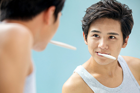 年轻男人对着镜子在刷牙图片