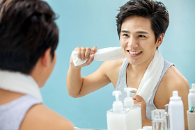 快乐的年轻男人拿着毛巾照镜子