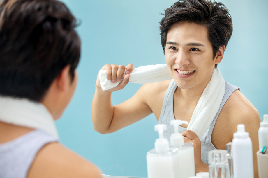 快乐的年轻男人拿着毛巾照镜子 快乐的年轻男人拿着毛巾照镜子