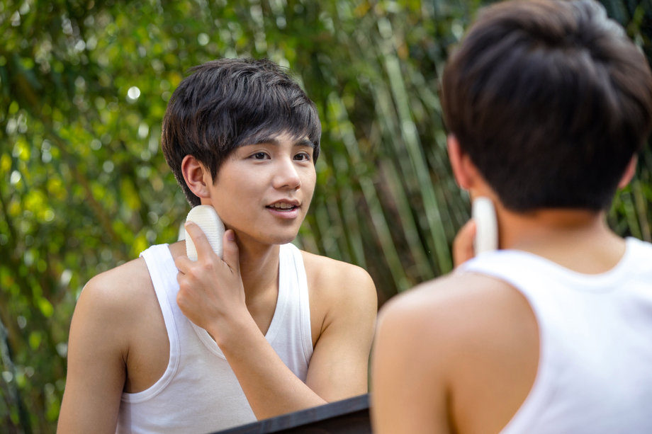 户外对着镜子用面扑洗脸的年轻男人