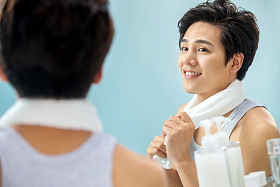 快乐的年轻男人拿着毛巾照镜子