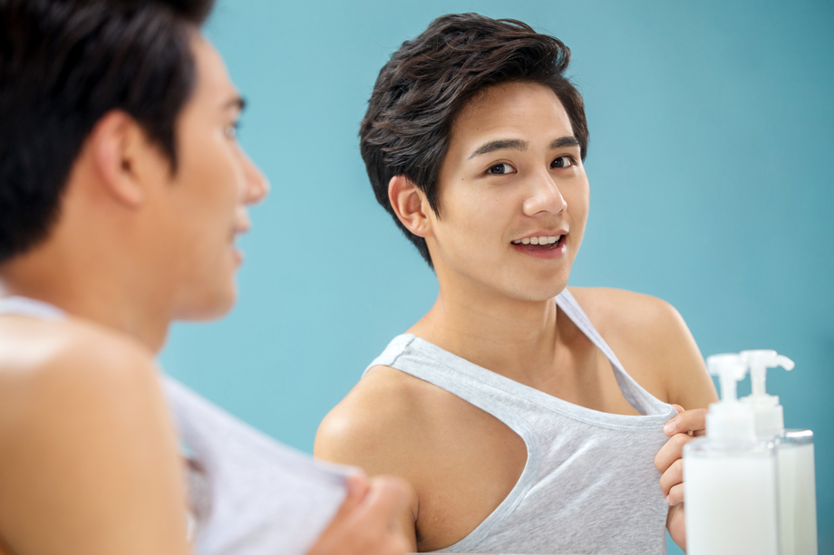 扯着背心照镜子的年轻男人图片