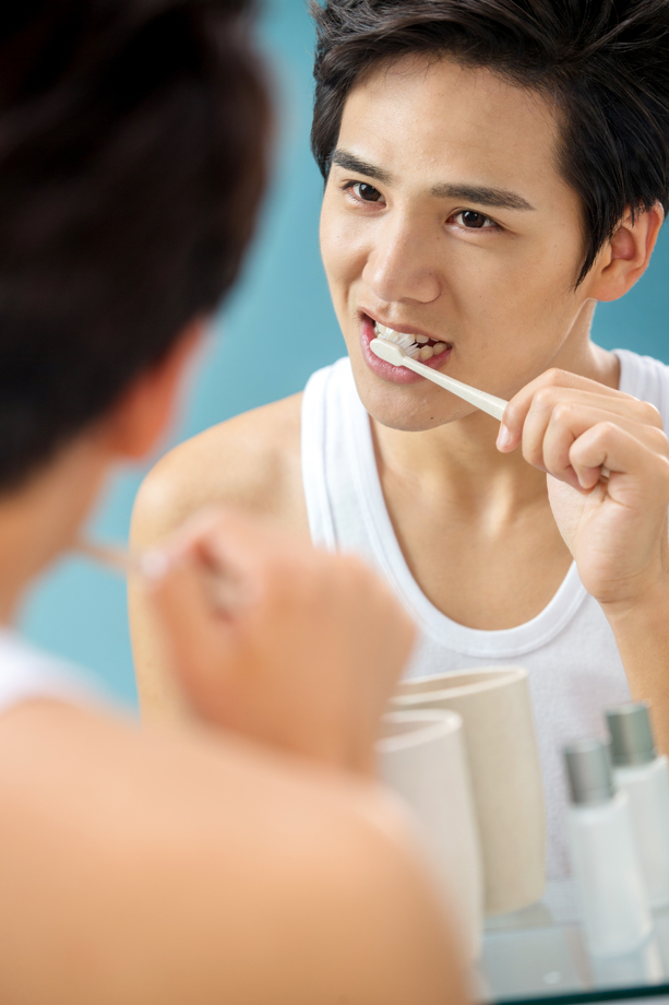 年轻男人对着镜子在刷牙图片