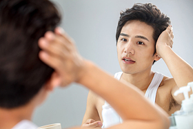 照着镜子整理发型的年轻男人