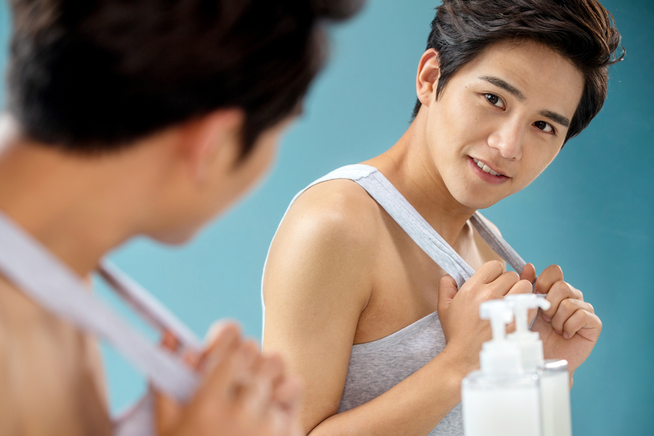 扯着背心照镜子的年轻男人图片