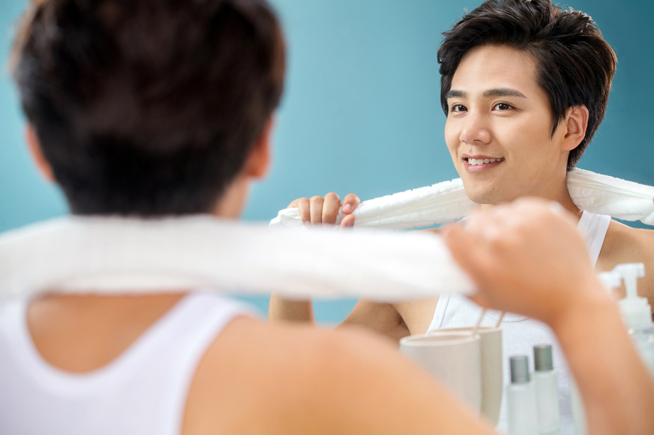 快乐的年轻男人拿着毛巾照镜子 快乐的年轻男人拿着毛巾照镜子