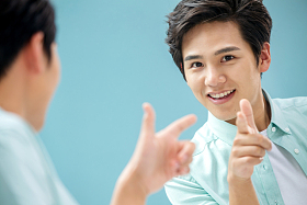 自信的年轻男人对着镜子做手势