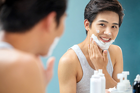 青年男人对着镜子涂抹剃须膏照片