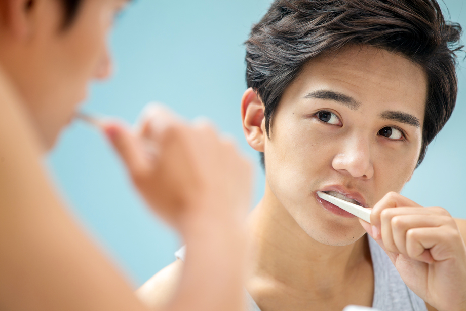 年轻男人对着镜子在刷牙图片