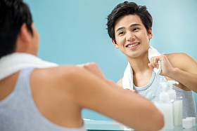 快乐的年轻男人拿着毛巾照镜子