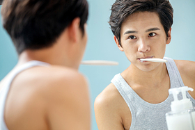 年轻男人对着镜子在刷牙照片