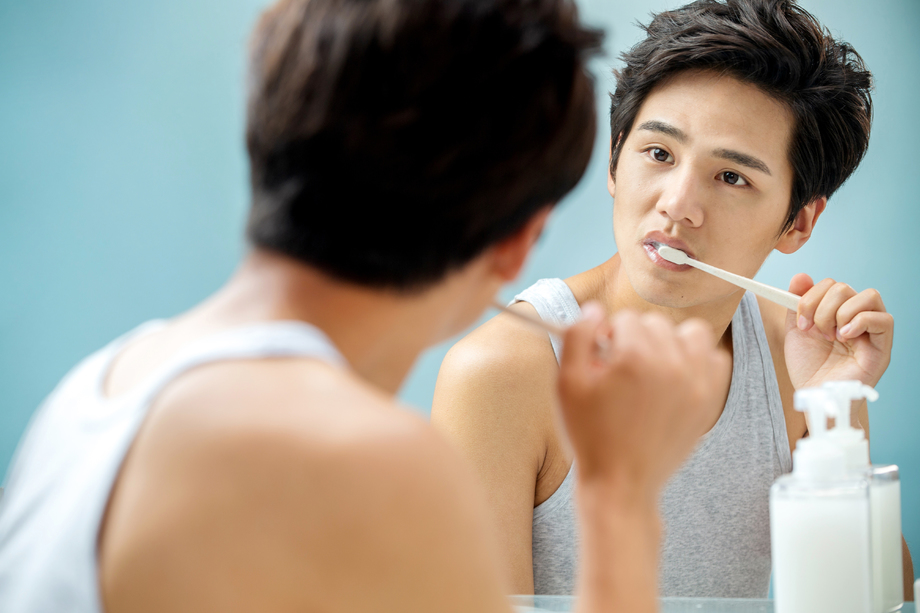 年轻男人对着镜子在刷牙