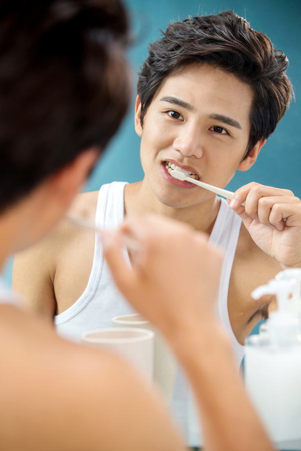 年轻男人对着镜子在刷牙