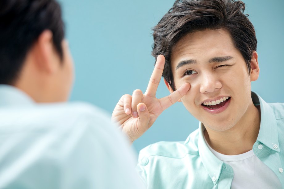 自信的年轻男人对着镜子做手势