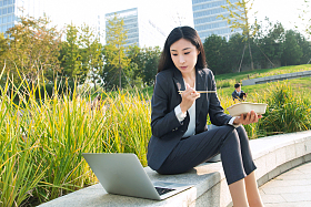 商务女性坐着户外边吃饭边工作
