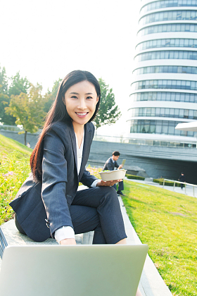 商务女性坐着户外边吃饭边工作