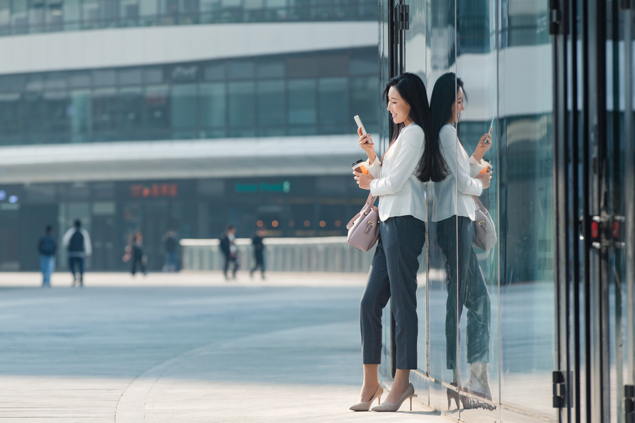 站在户外看手机的商务女性