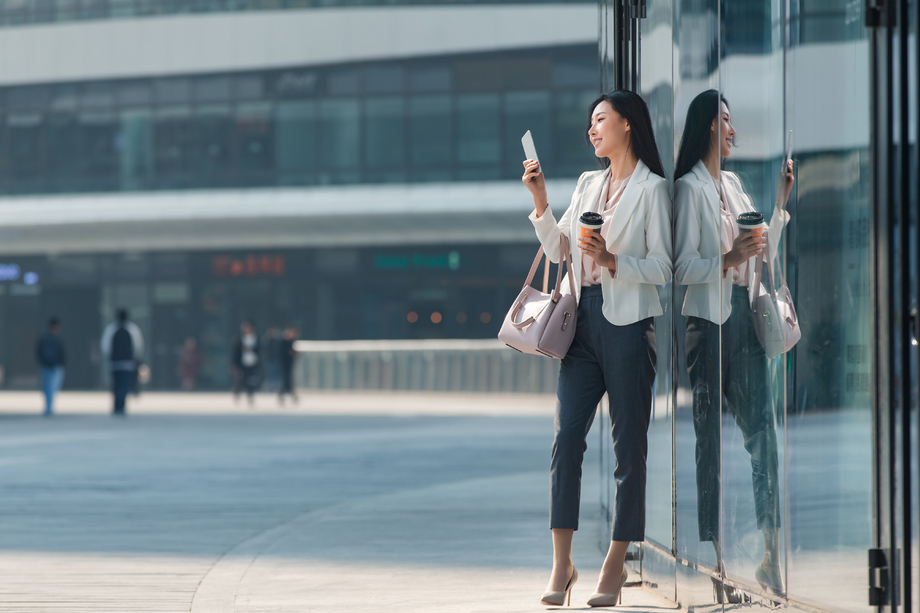 站在户外看手机的商务女性