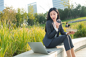 商务女性坐着户外边吃饭边工作