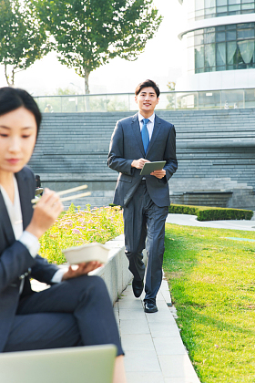 商务女性坐着户外边吃饭边工作