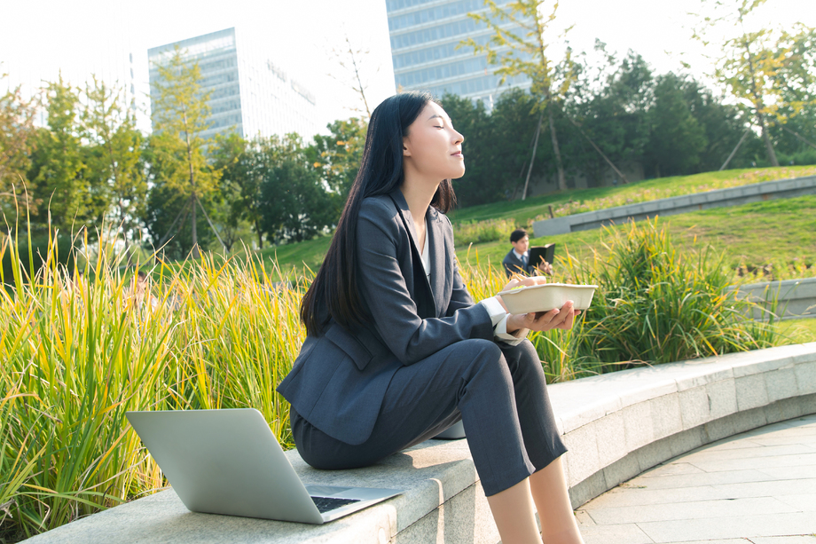 商务女性坐着户外边吃饭边工作 商务女性坐着户外边吃饭边工作