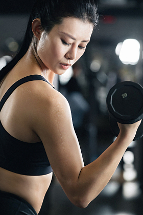 年轻女子在健身房练习举哑铃照片