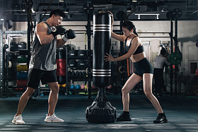 健身房内教练指导年轻男子打拳击