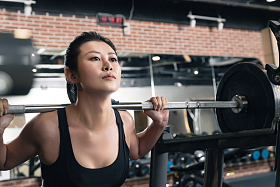 年轻女子在健身房练习抗杠铃图片