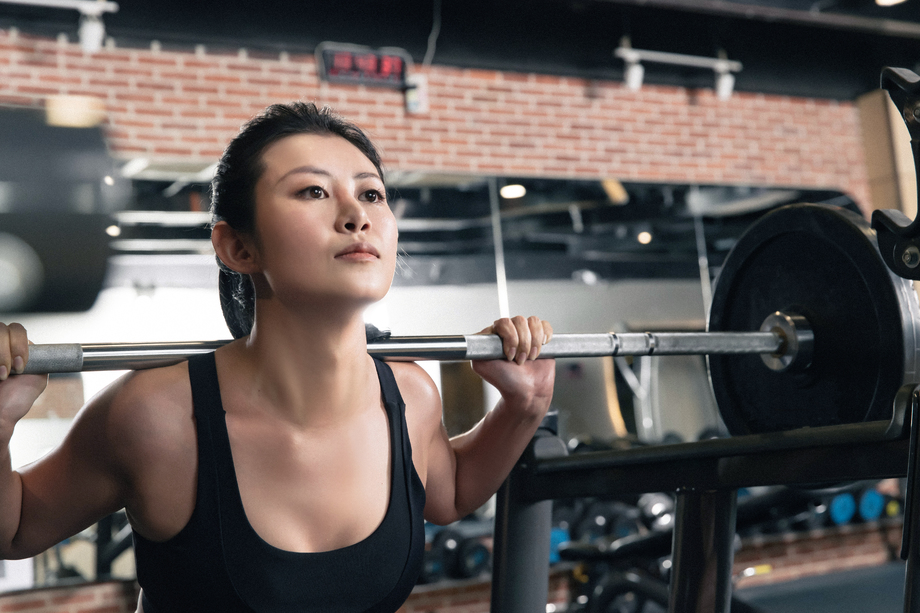年轻女子在健身房练习抗杠铃图片