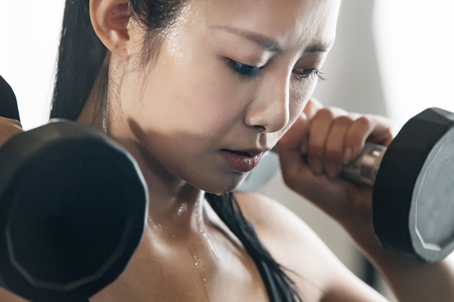 年轻女子在健身房练习举哑铃图片