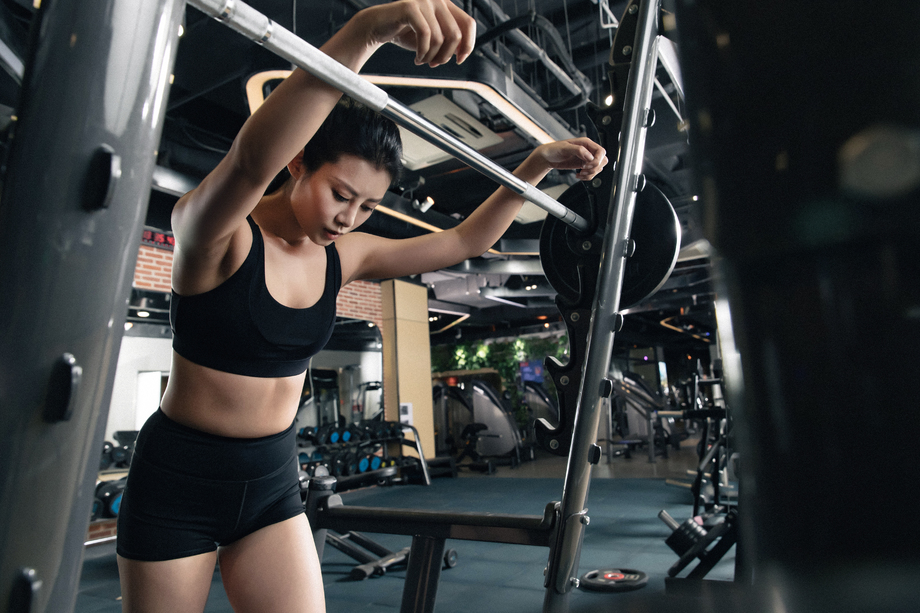 健身房里年轻女子趴在杠铃上休息 健身房里年轻女子趴在杠铃上休息